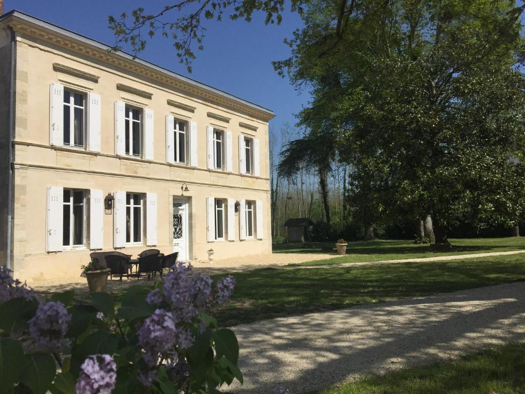 un grand bâtiment blanc avec des fleurs devant lui dans l'établissement Domaine Cazenave, à Budos