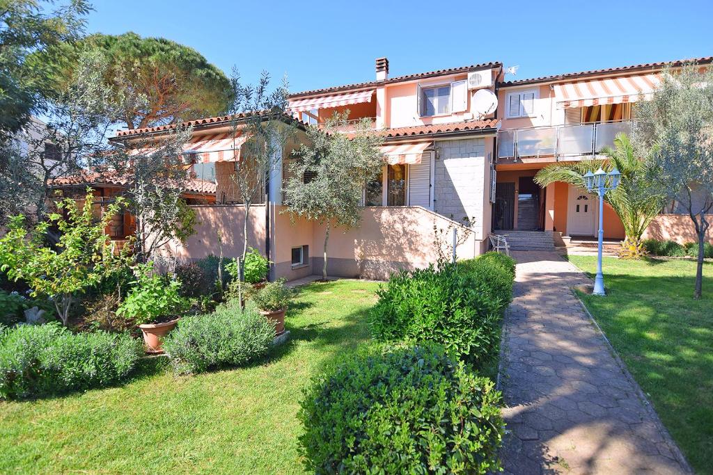 a house with a yard with bushes and trees at Apartments Jeromela in Fažana