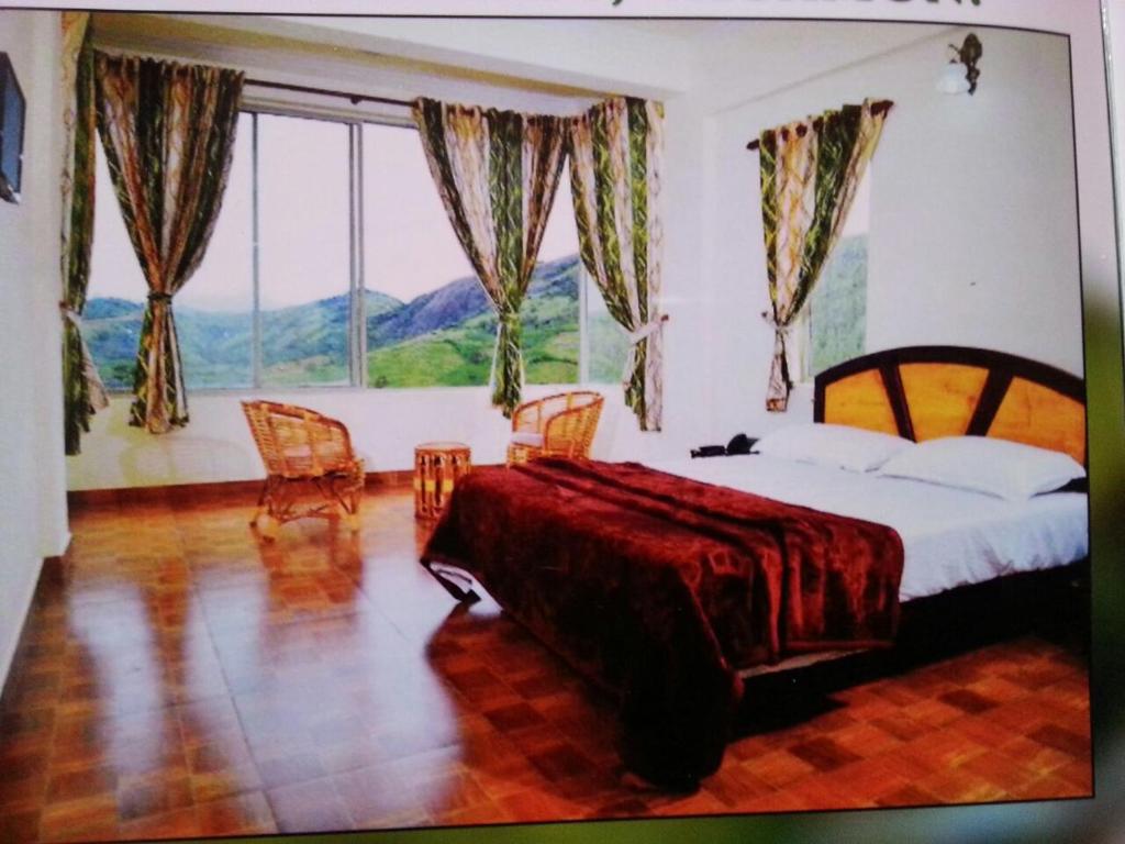 a bedroom with a large bed and a large window at Vaga Hills Resort in Vagamon