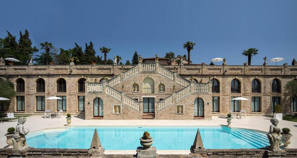 Villa Cattani Stuart XVII secolo في بيزارو: مبنى من الطوب كبير مع مسبح كبير