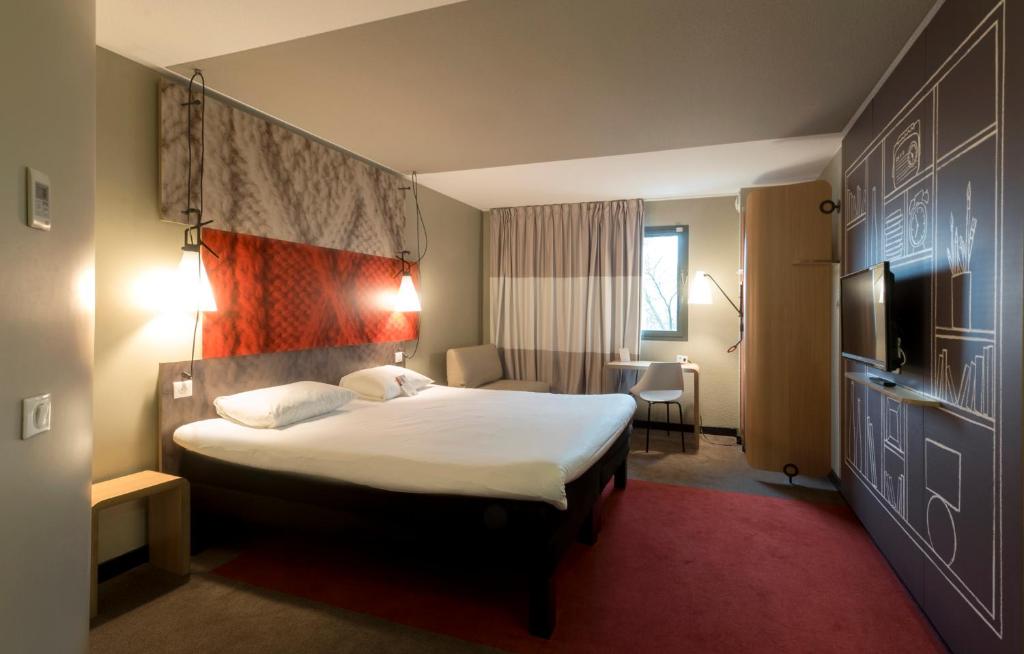 a hotel room with a bed and a tv at ibis Rouen Centre Champ de Mars in Rouen