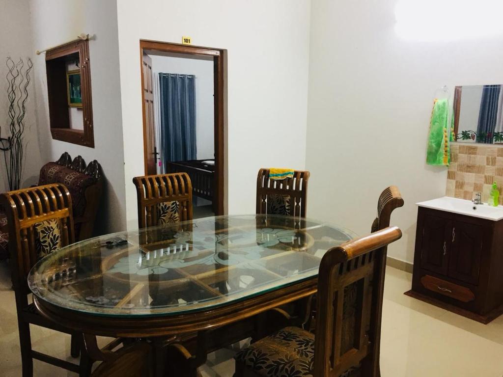 een eetkamer met een glazen tafel en stoelen bij White Clouds Cottage Munnar in Munnar