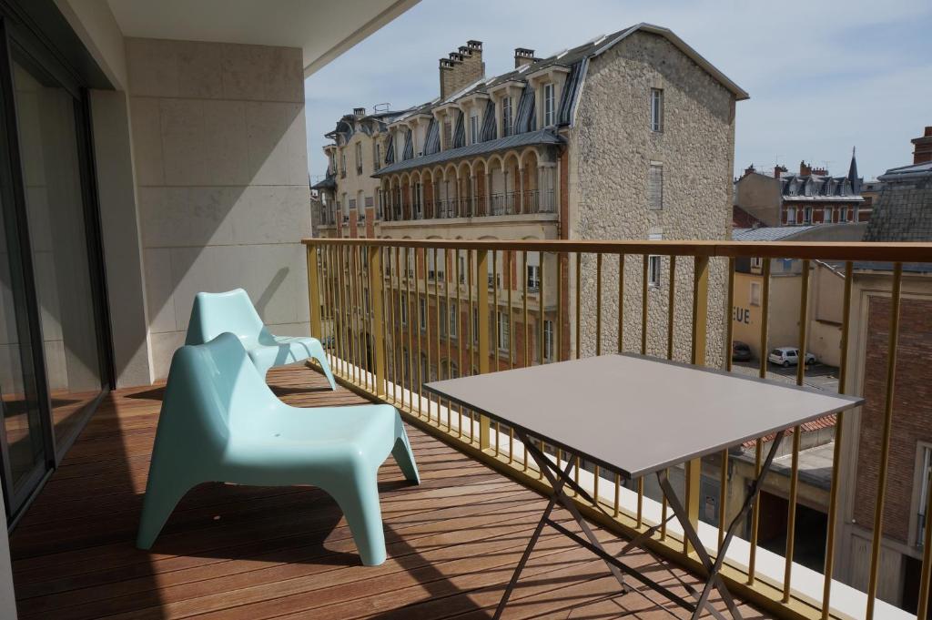 Appartement Forum Reims في رانس: كرسي ازرق وطاولة على بلكونه