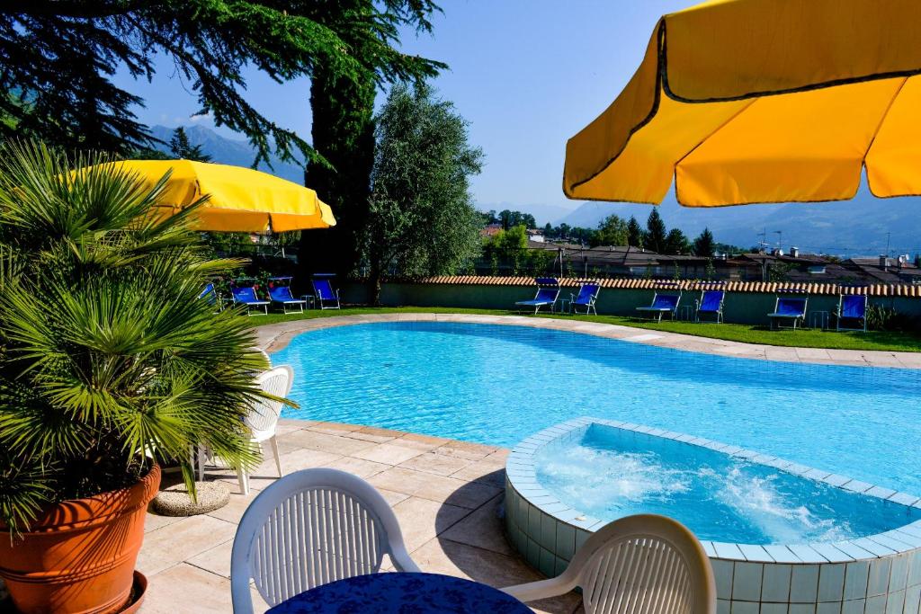 een zwembad met stoelen en parasols en een tafel en stoelen bij Kröllnerhof in Lana