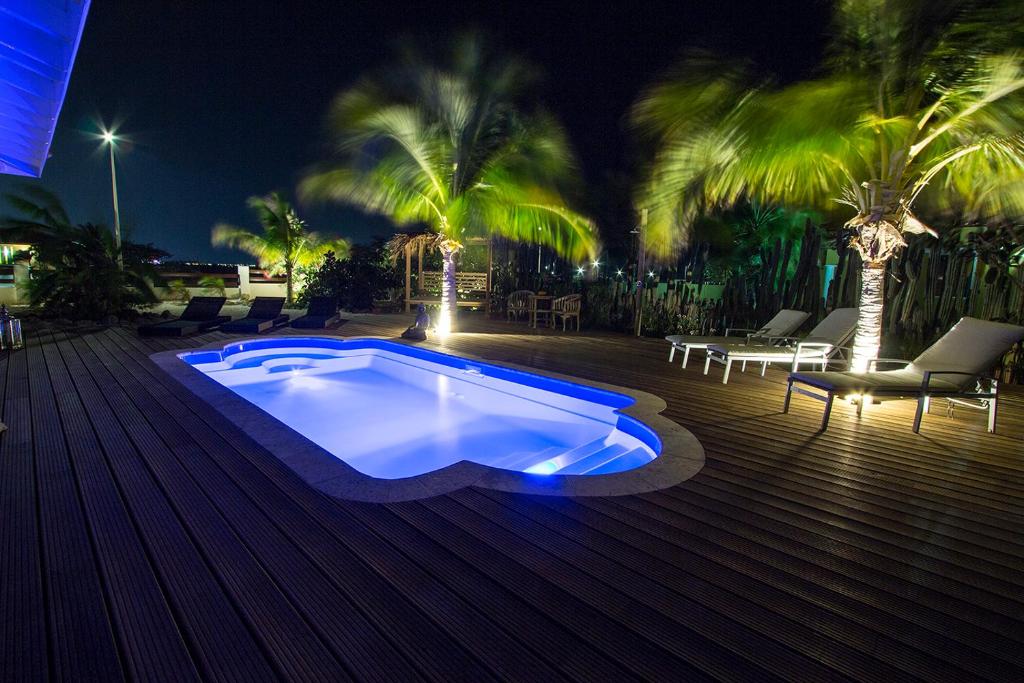 una piscina por la noche con palmeras en Kas Rolo, en Kralendijk