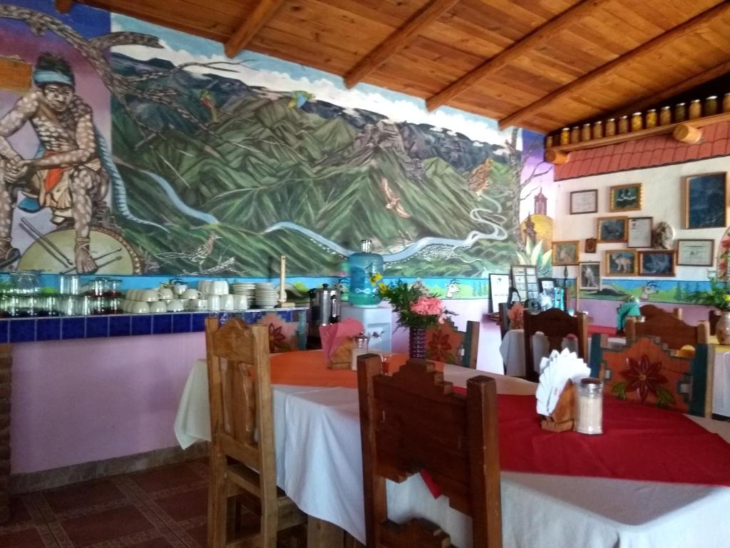 un comedor con un mural en la pared en Rancho Cabañas San Isidro en Cerocahuí