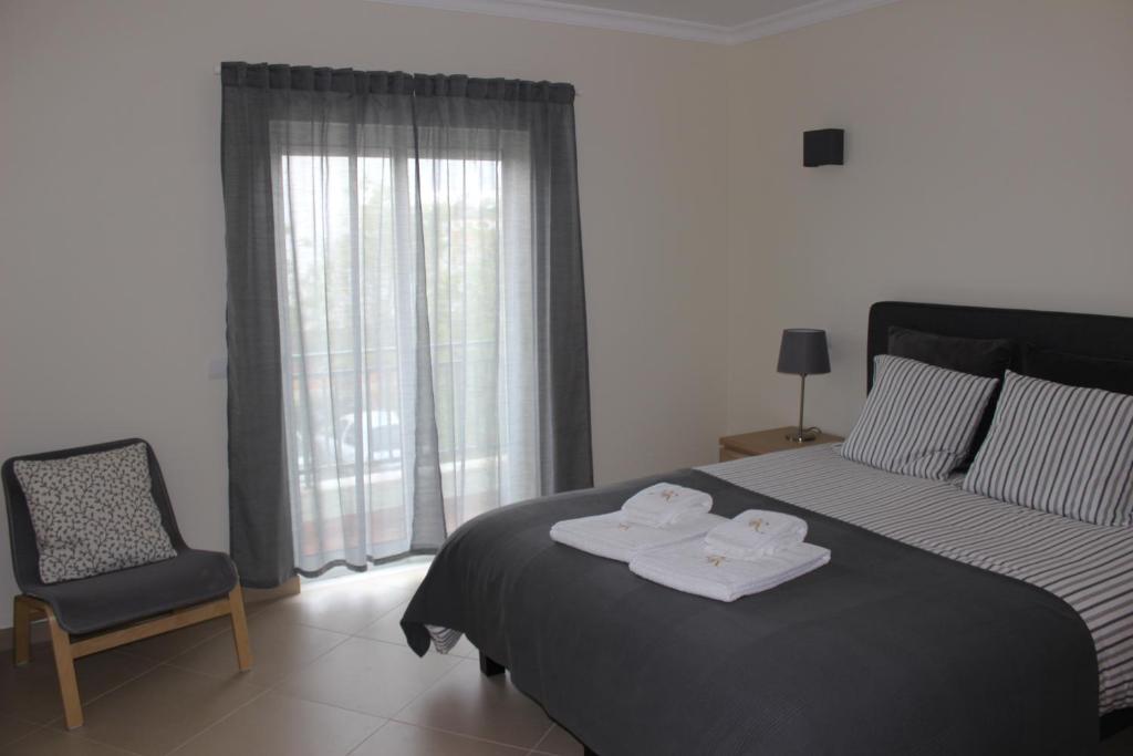 a bedroom with a bed and a chair and a window at Alta da Ria House in Cabanas de Tavira