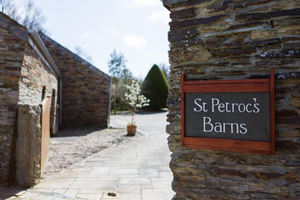 a sign on the side of a stone building with a sign for st patricks at Re-imagined Stone Barns in the Country Near the Coast in Padstow