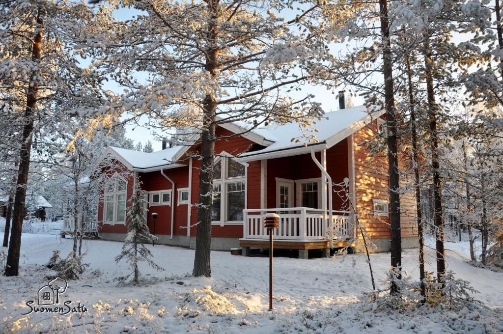 una casa roja en la nieve con árboles nevados en LevinSatu: SeLevi and TaLevi Apartments, en Levi