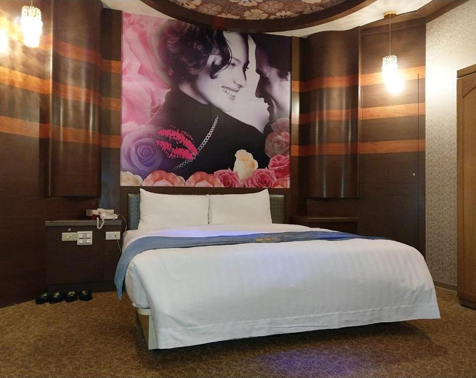 a bedroom with a bed with a painting on the wall at Beidoo Hotel in Keelung