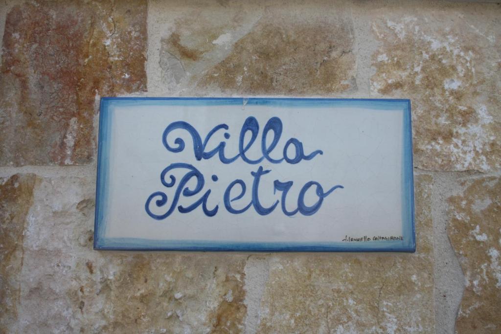 a sign on a brick wall with the word alla extra at Villa Pietro in Ispica