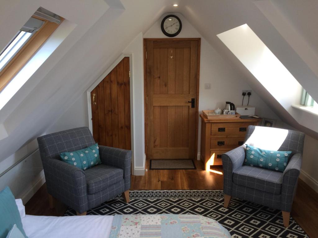 a attic room with two chairs and a clock at Pump View in Weymouth