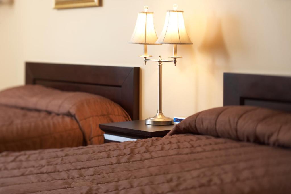 Innisfail的住宿－Travel Inn & Suites，酒店客房设有两张床和一张桌子上的台灯。