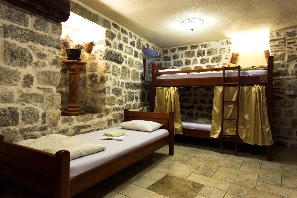 a bedroom with two bunk beds in a stone wall at Old Town Youth Hostel in Kotor