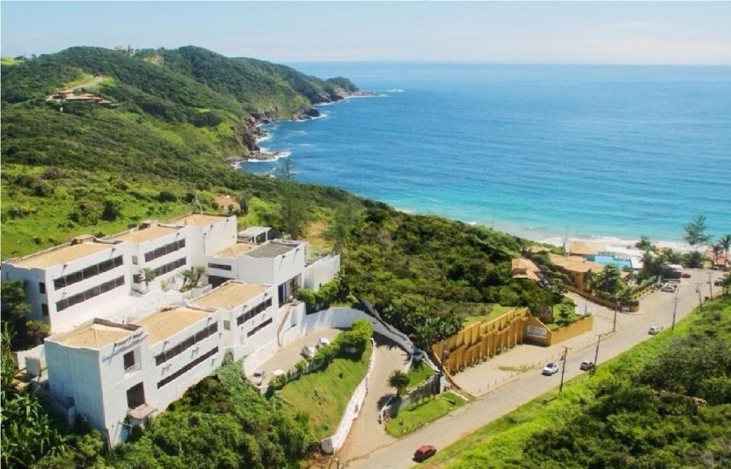 a building on a hill next to the ocean at Greco Hotel in Búzios