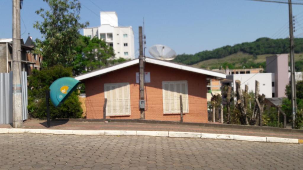 mały budynek z niebieskim parasolem przed nim w obiekcie Casa para 12 pessoas w mieście Piratuba