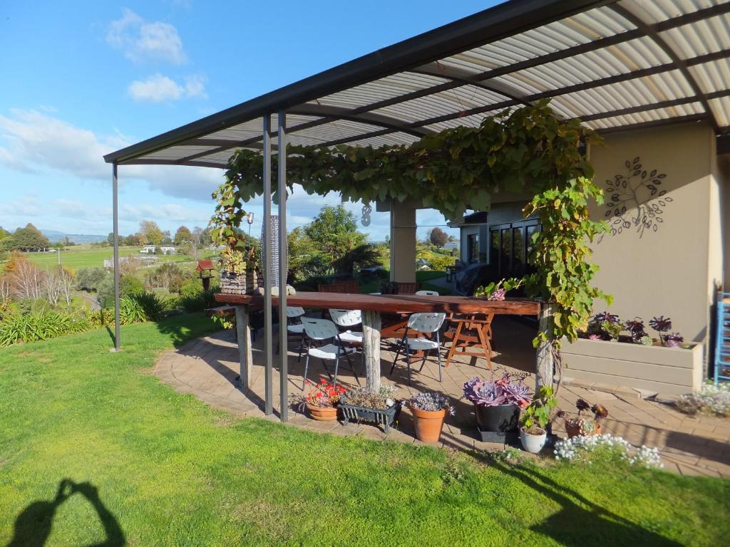 a pergola with a table and chairs in a yard at Waitomo Golfstays B&B in Otorohanga