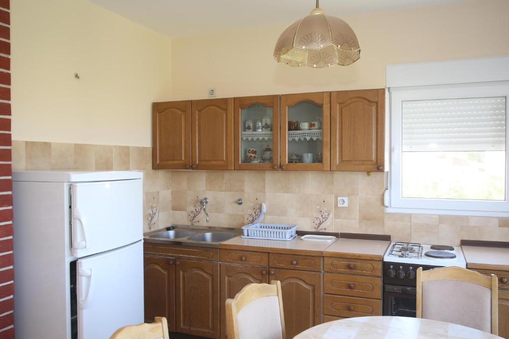 kuchnia z drewnianymi szafkami i białą lodówką w obiekcie Apartment Michelle w Bibinje