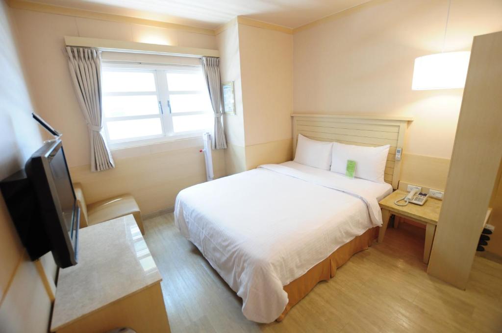 a small room with a bed and a television at Kindness Hotel - Tainan Minsheng in Tainan