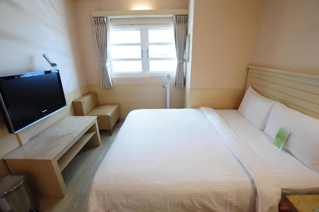 a hotel room with a large bed and a television at Kindness Hotel - Tainan Minsheng in Tainan
