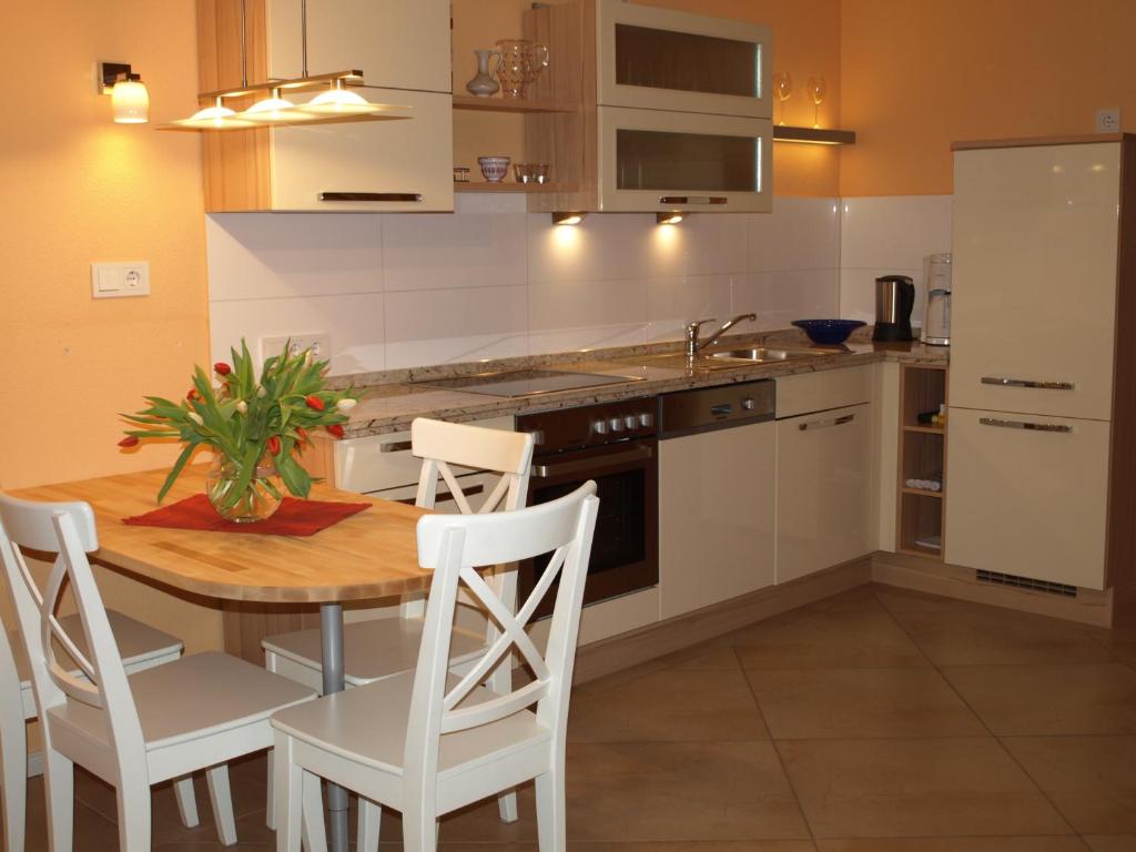 cocina con mesa de madera y armarios blancos en Ferienhaus Fischlandperle, en Wustrow