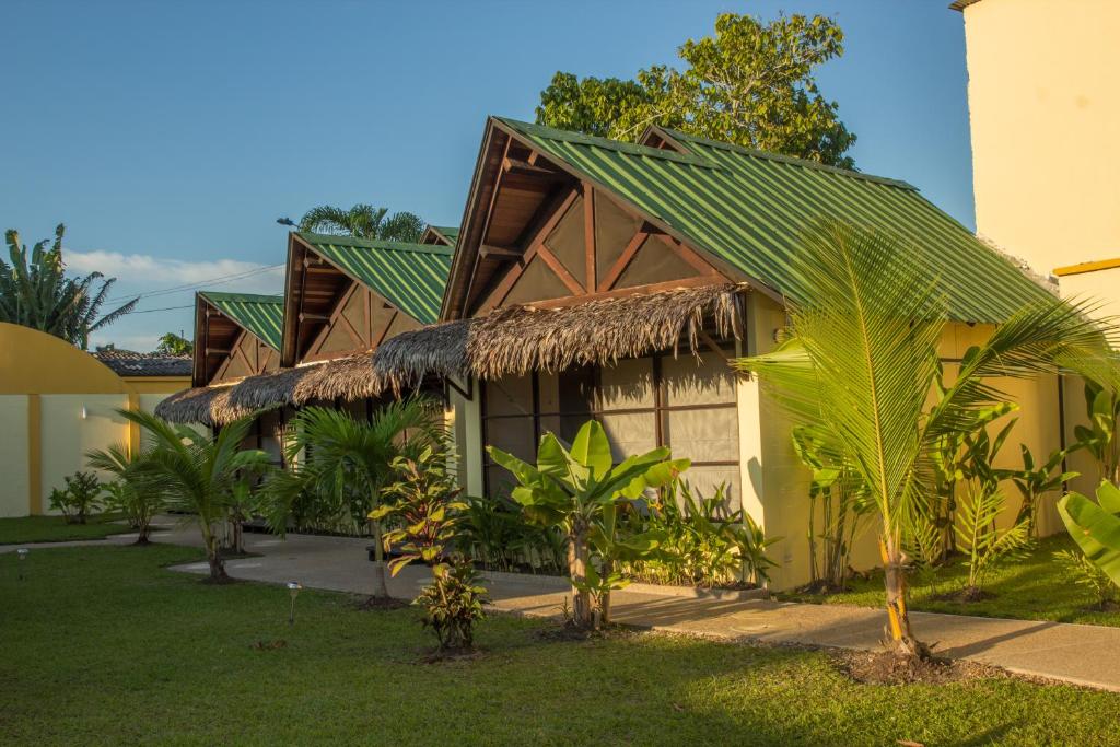a green and white house with trees and palm trees at Hotel Amazon Bed And Breakfast in Leticia