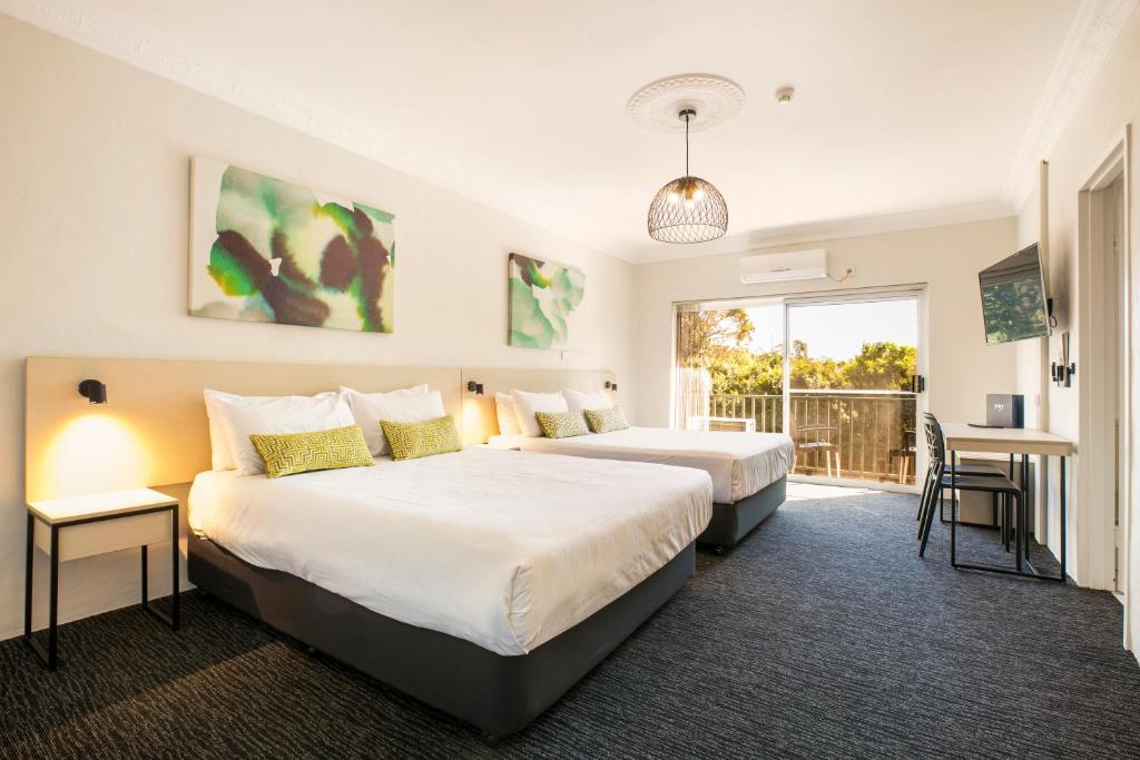 a hotel room with two beds and a balcony at Nightcap at Blue Cattle Dog Hotel in Rooty Hill