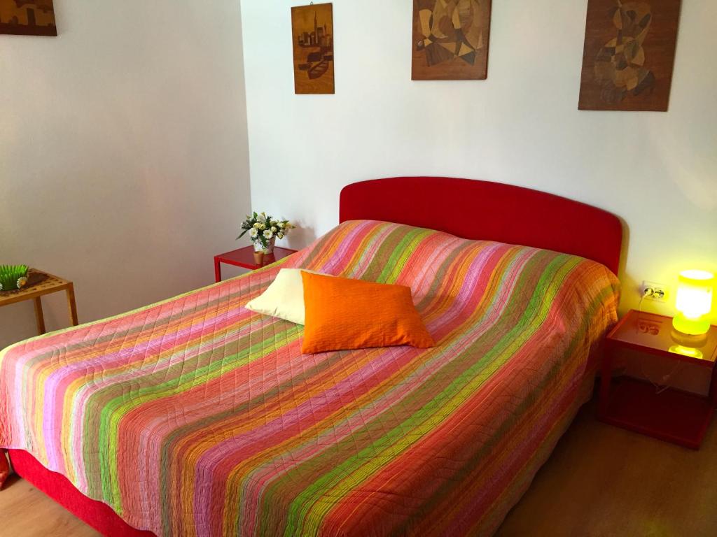 ein Bett mit einer bunten Decke und einem orangenen Kissen darauf in der Unterkunft Apartment Lavanda in Molat