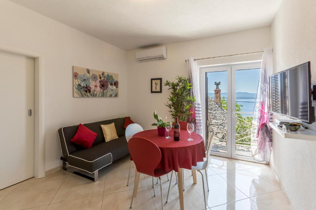 ein Wohnzimmer mit einem roten Tisch und einem Sofa in der Unterkunft Apartments Petra in Bol