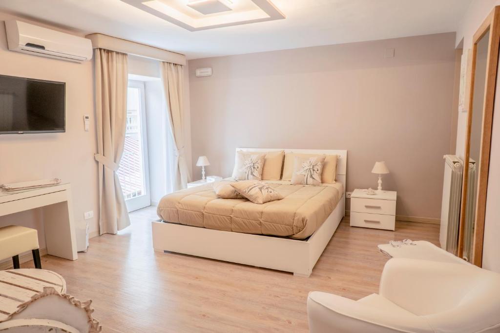 a white bedroom with a bed and a tv at Sirenide in Sorrento