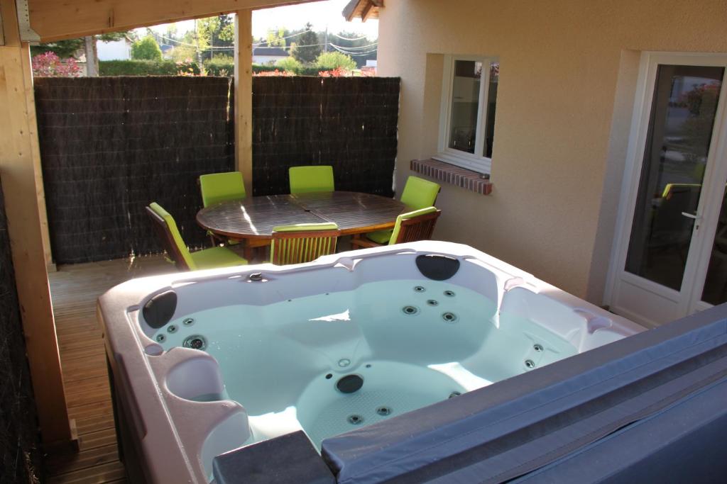 a jacuzzi tub on a patio with a table at ENTRE LOIRE ET CHER "Le Sologn'Eau" Gîte & SPA Privatif in Tour-en-Sologne