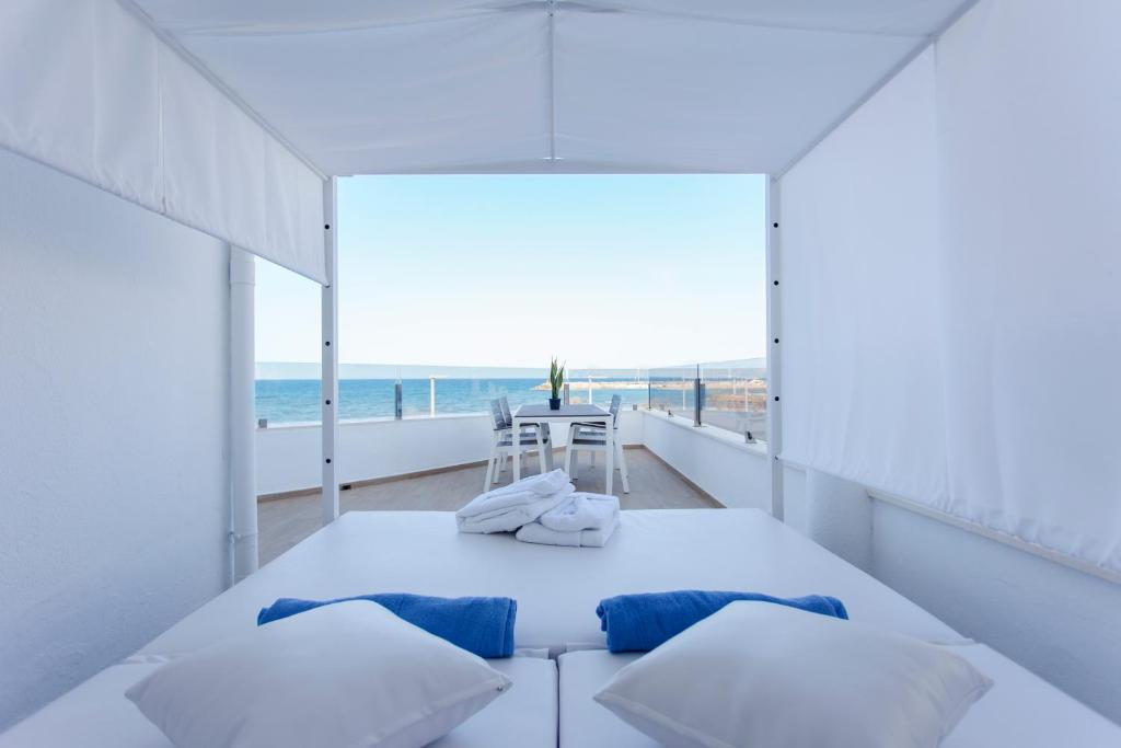 a white room with a bed and a view of the ocean at Apartamentos Ses Roquetes in Can Picafort