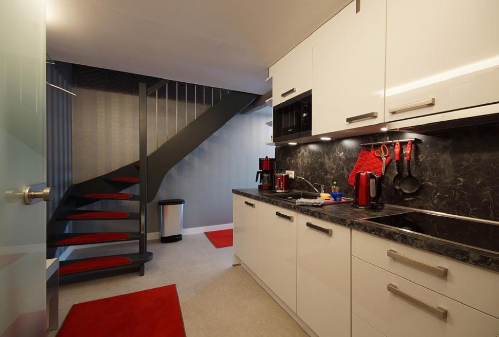 una cocina con armarios blancos y una escalera negra en Ferienhof Elbaue en Schönebeck