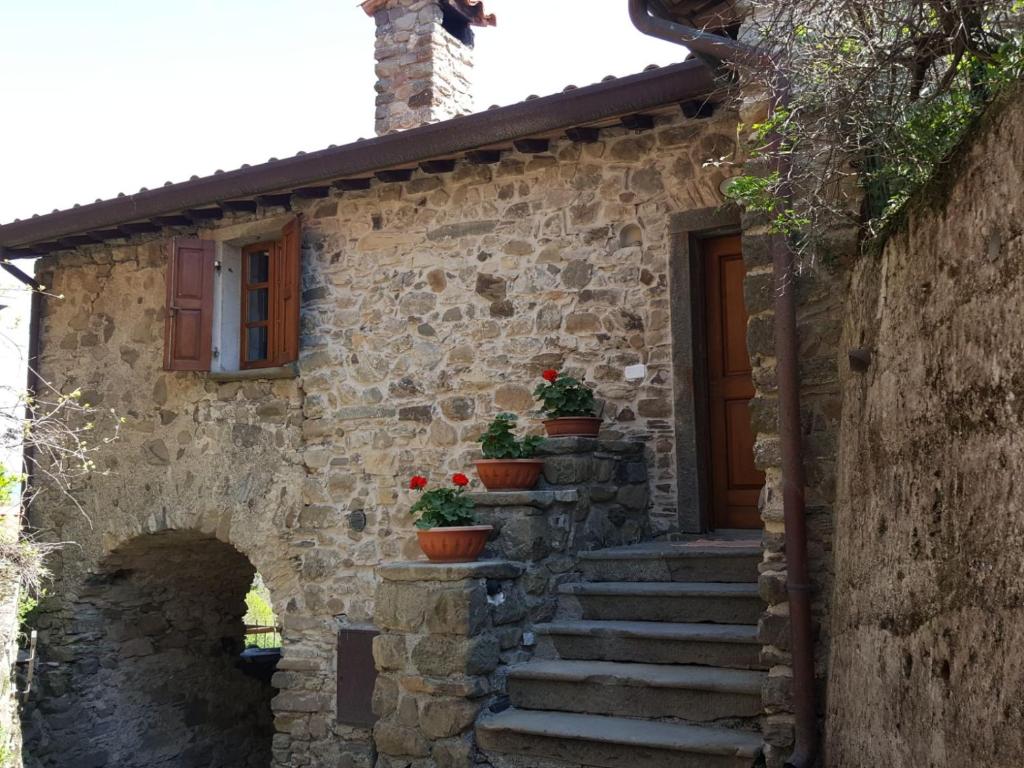 een oud stenen huis met potplanten op de trap bij Casa Bensaia in Mulazzo