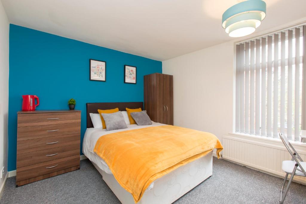 a bedroom with a bed with a blue accent wall at Townhouse @ Edleston Road Crewe in Crewe