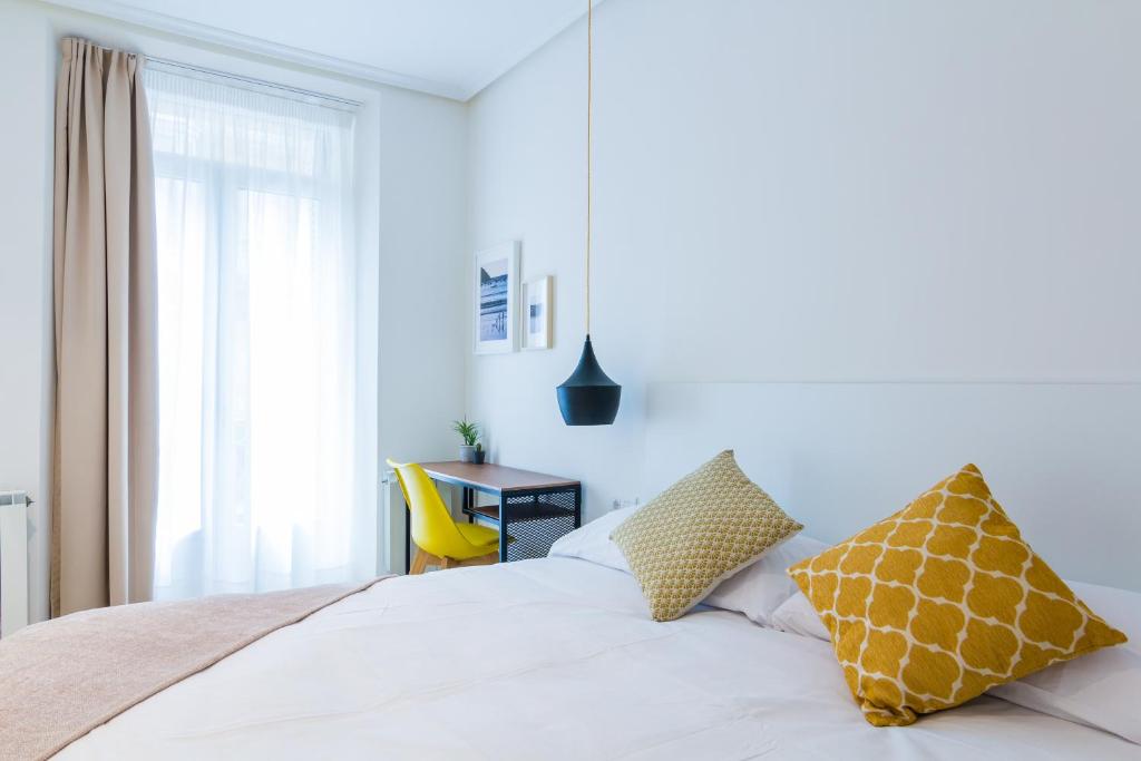 a bedroom with a white bed with yellow pillows at Pensión Buenpas in San Sebastián