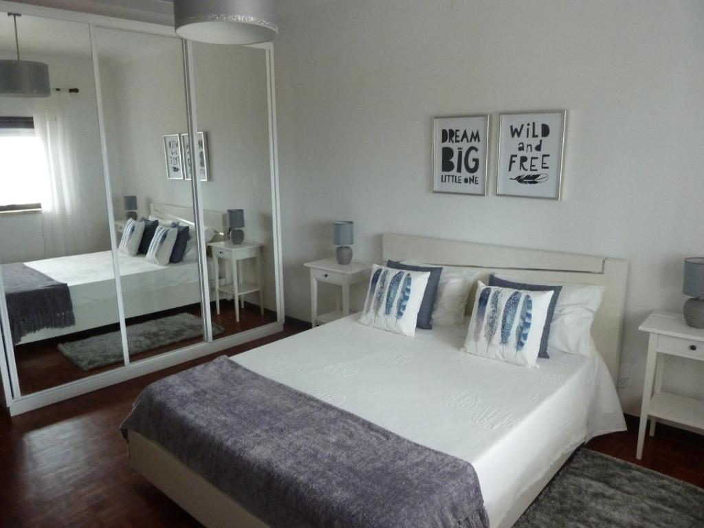 una camera da letto con un grande letto bianco e uno specchio di Casa do Norte a Nazaré