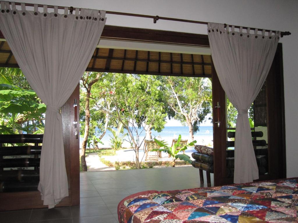 a bedroom with a bed and a view of the beach at Bali Dream House in Amed