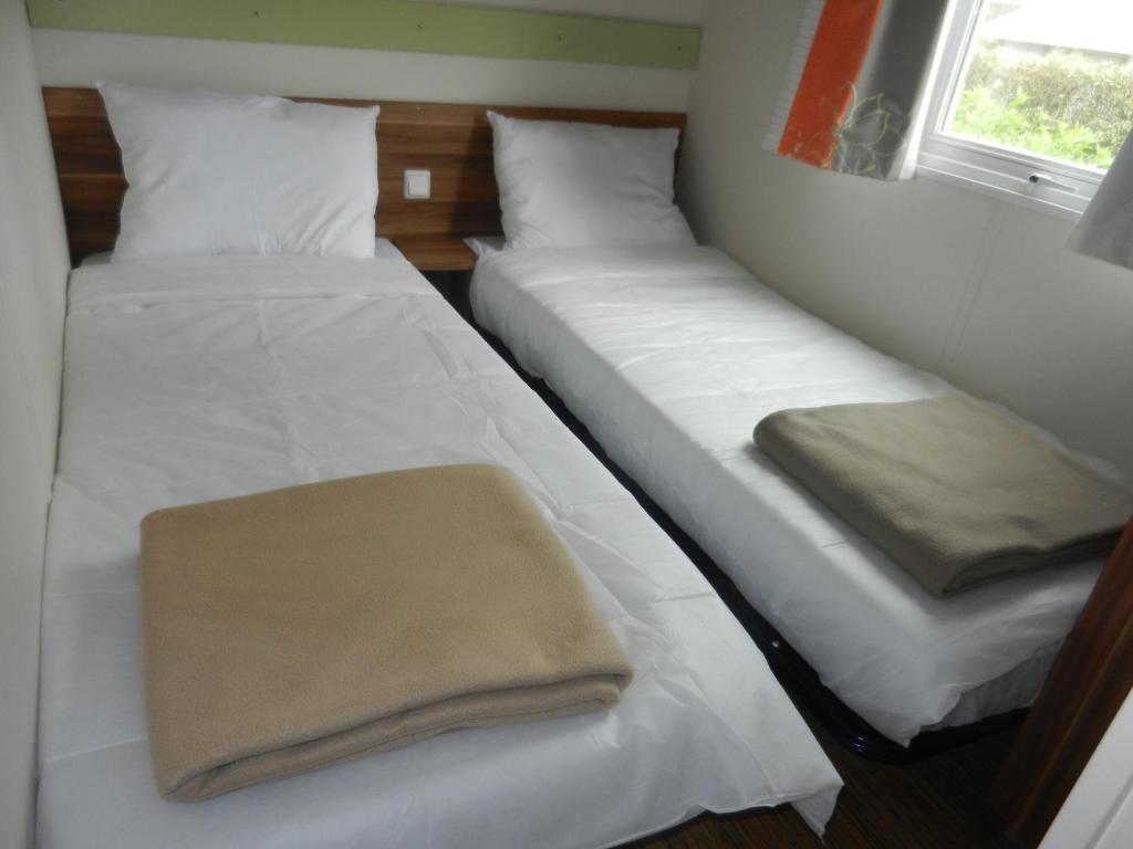 two beds in a room with white sheets and a window at Mareva37 in Trogues