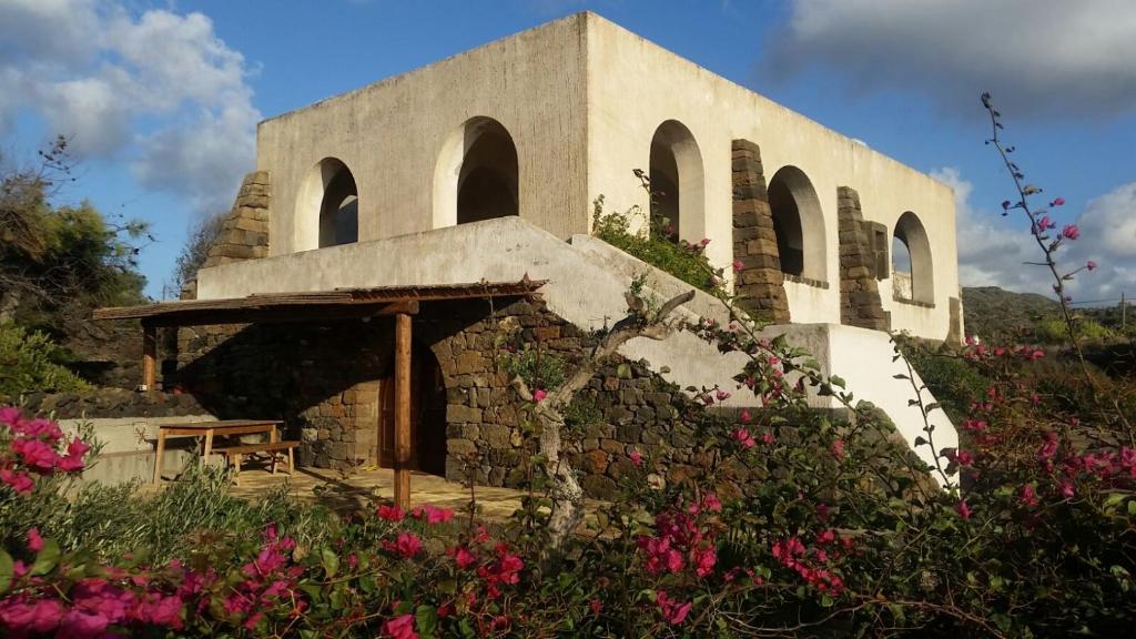 a building with some pink flowers in front of it at Mursia Casa Vacanze in Pantelleria