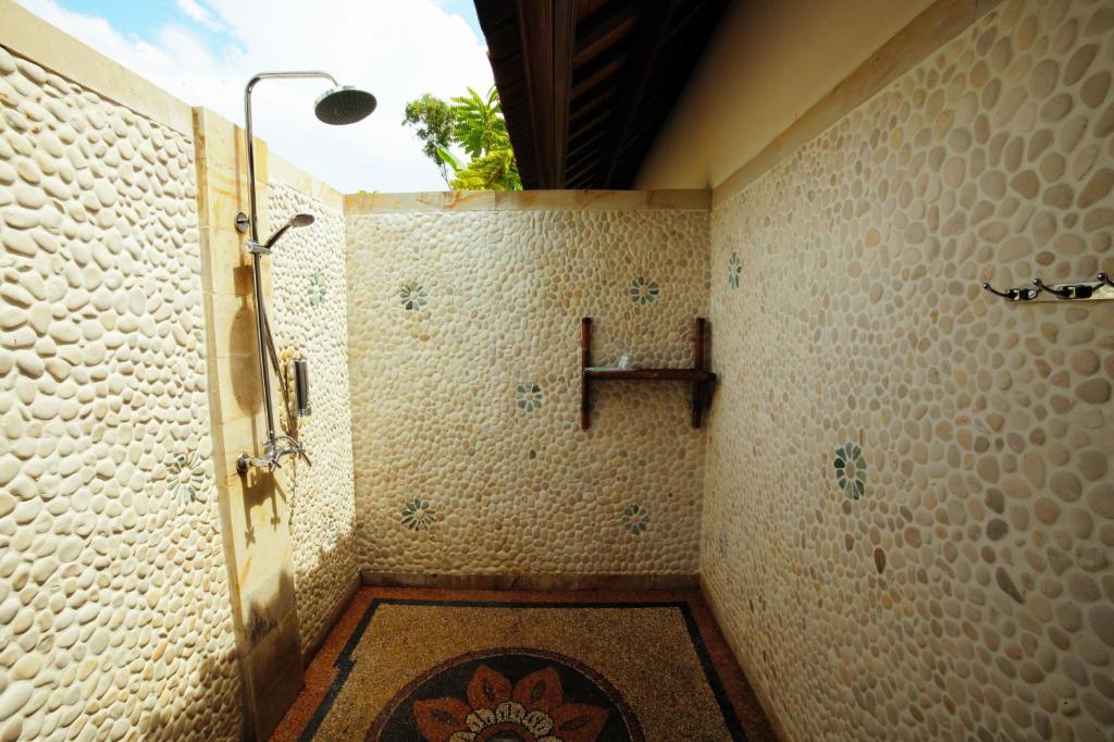 a bathroom with a shower with a plant on the wall at Bali Dream House in Amed