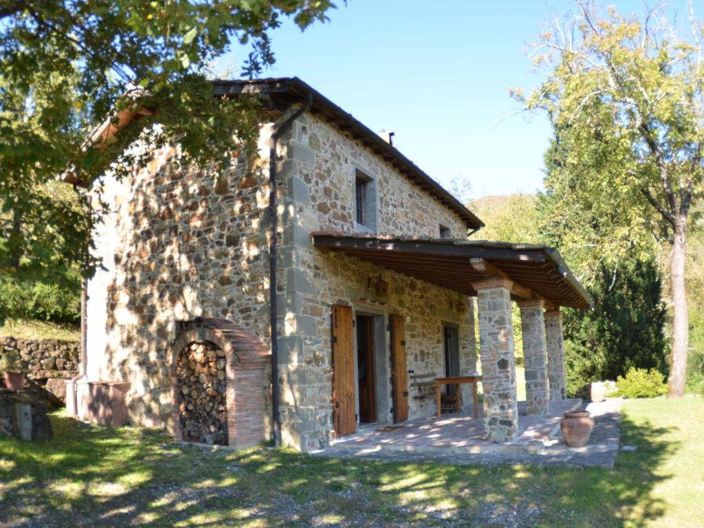 uma antiga casa de pedra com um alpendre num campo em Lovely Cottage in Bagni di Lucca Amidst Fields em Longoio