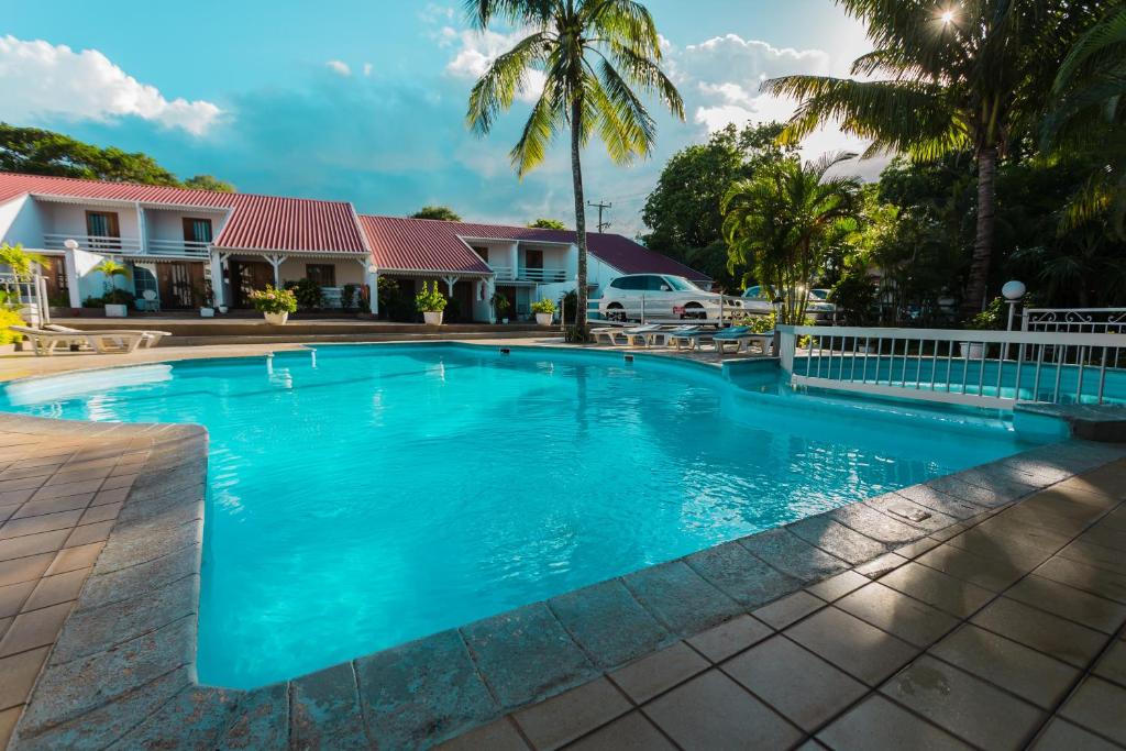 a swimming pool in front of a house with palm trees at Residence Villas Mont Choisy in Mont Choisy