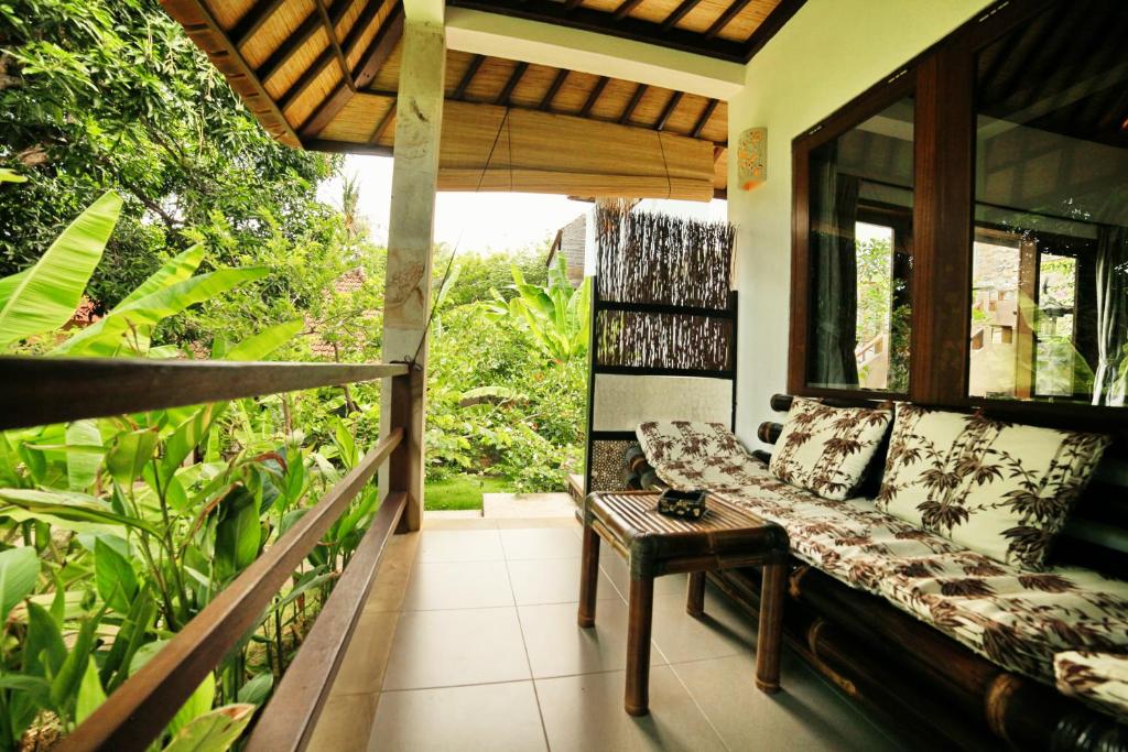 a porch with a couch and a table at Bali Dream House in Amed
