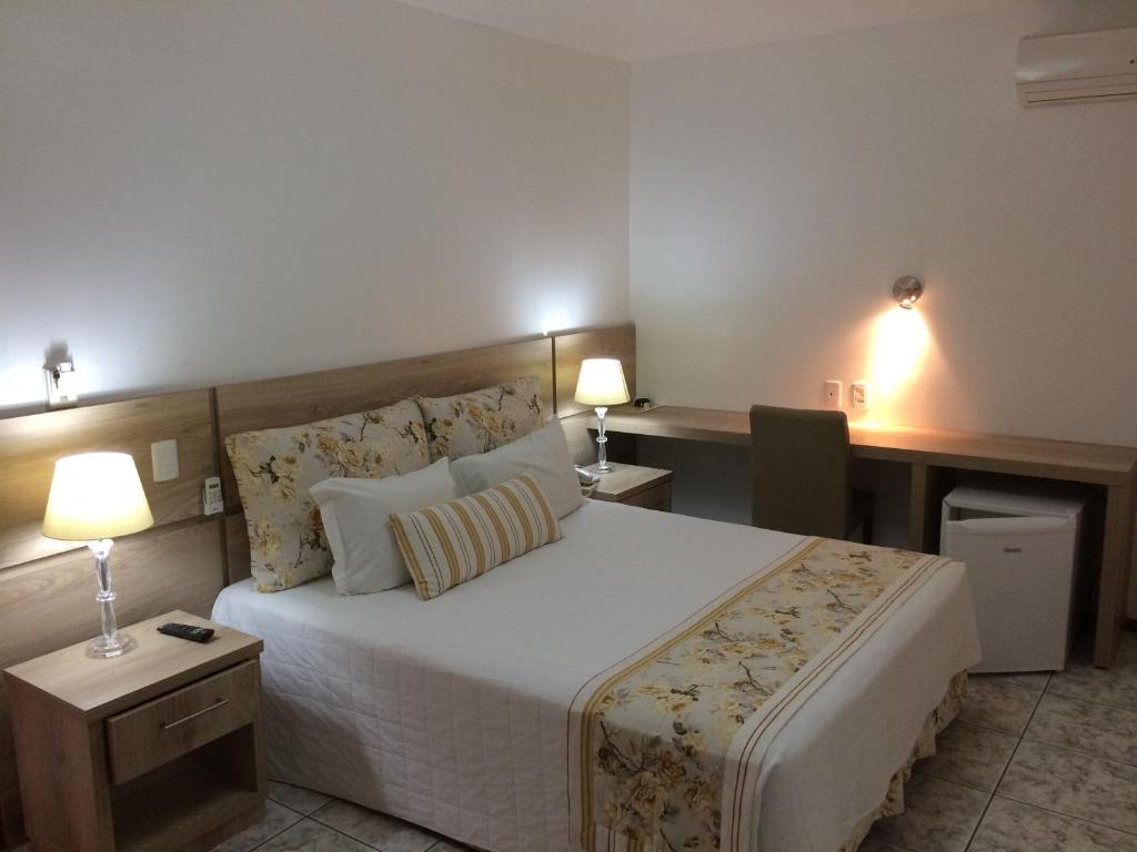 1 dormitorio con 1 cama grande, 2 mesas y 2 lámparas en Schenkel Hotel, en Tramandaí