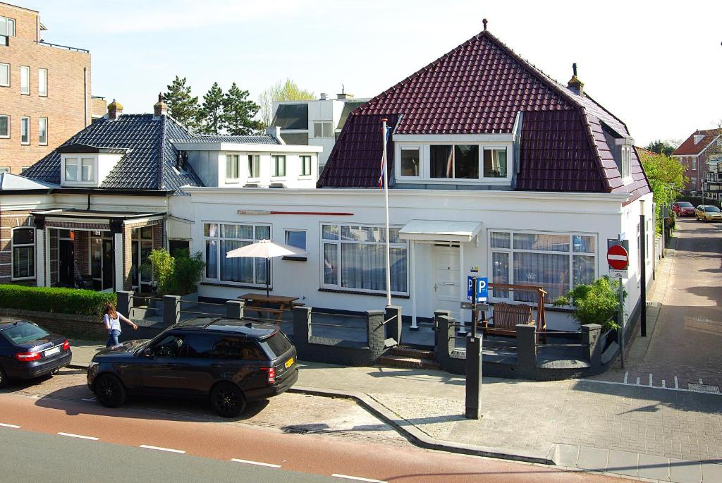 a white house with a car parked in front of it at Hotel Zand in Zandvoort