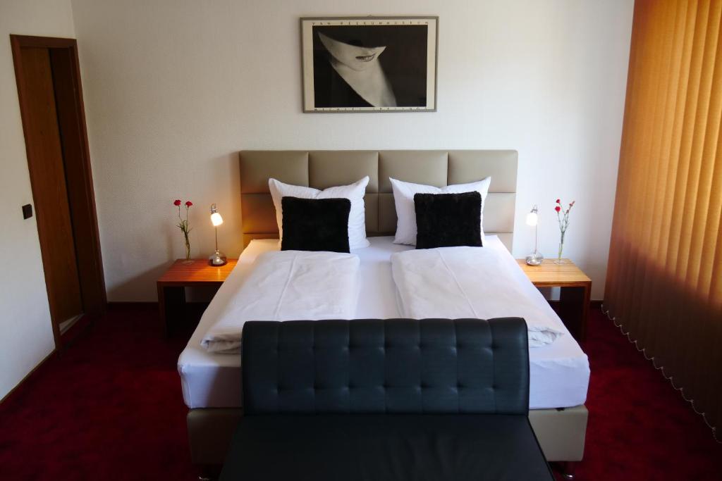 a bedroom with a large white bed with black pillows at Parkhotel Bergheim in Bergheim