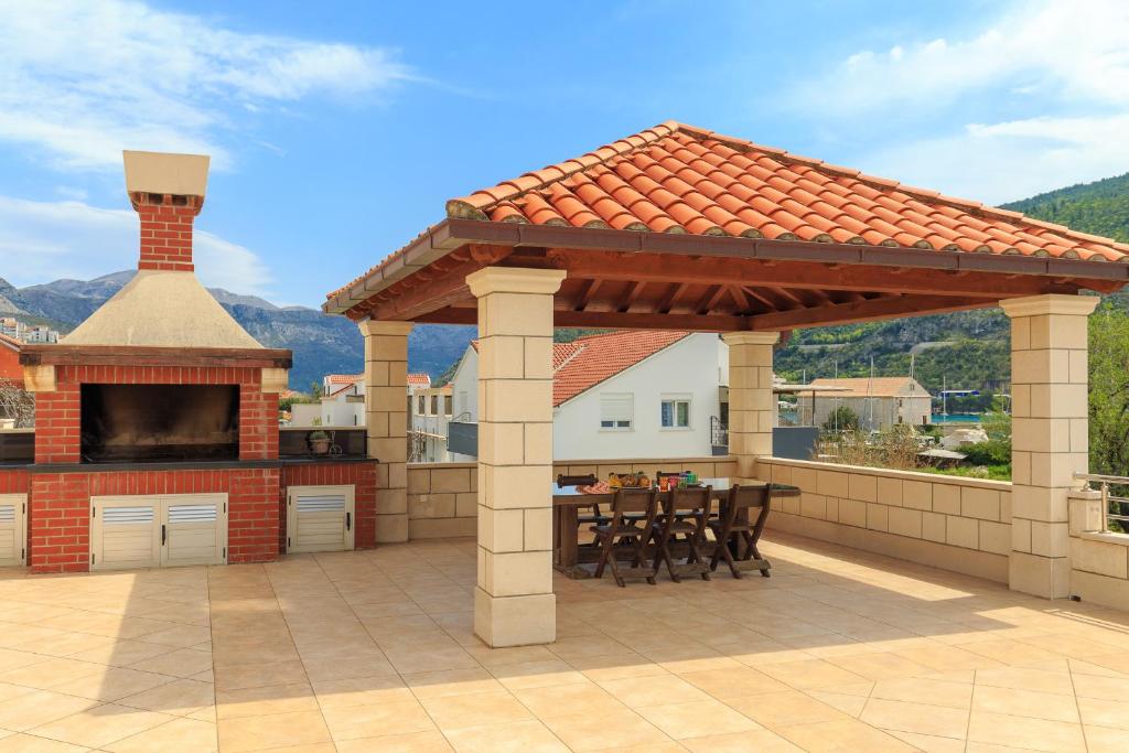 a pavilion on a patio with a table and a fireplace at Apartments Mondo in Mokošica
