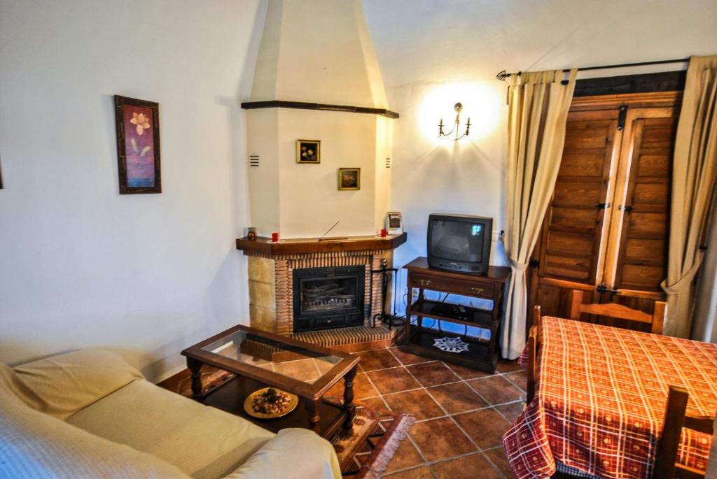 sala de estar con sofá y chimenea en Cortijo Las Monjas, en Periana