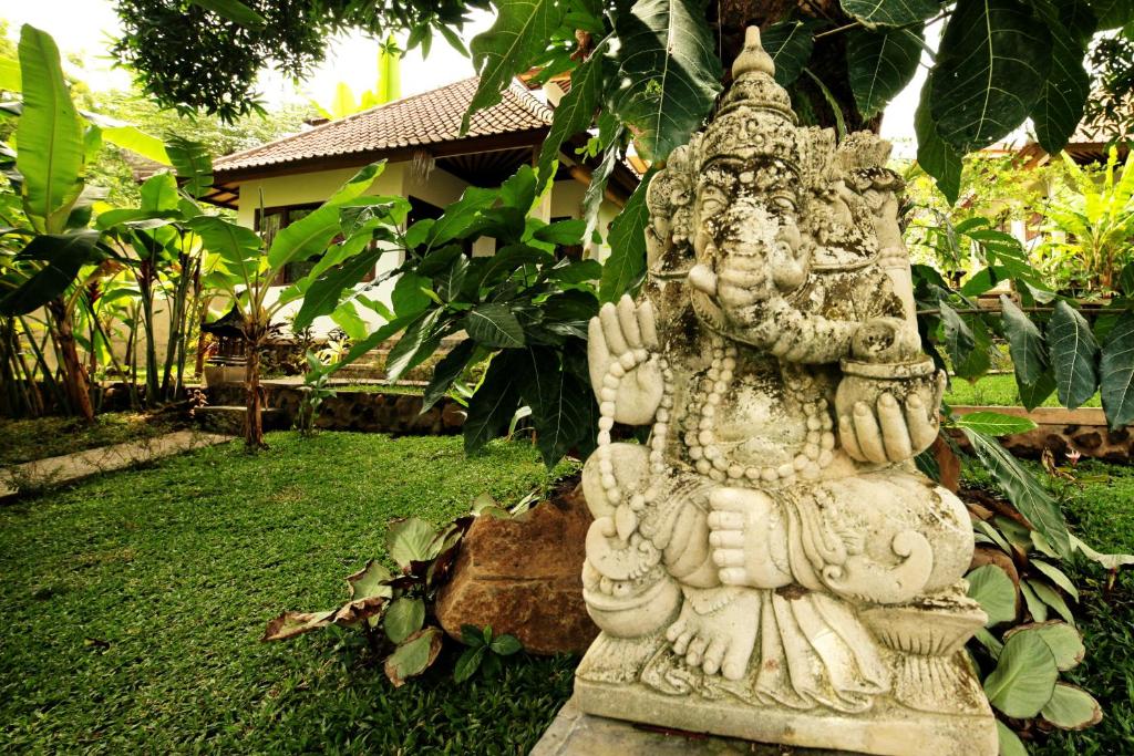 a statue of a deity standing in a garden at Bali Dream House in Amed